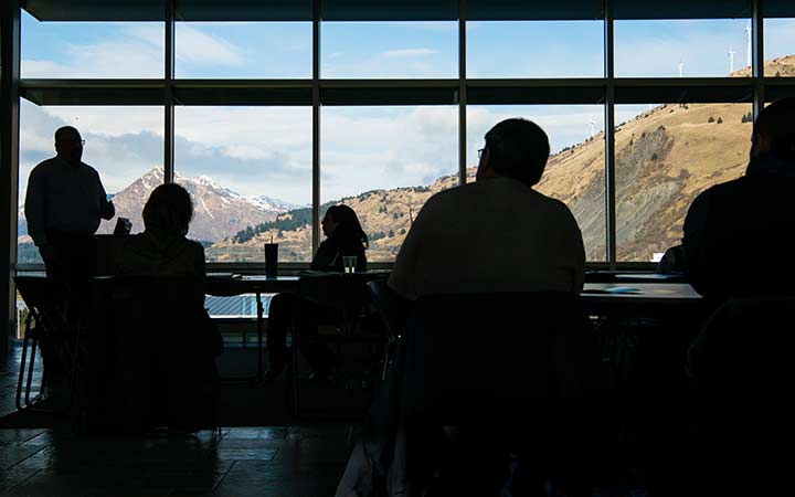 research-areas-slt-51184 Silhoutted workshop participants with large windows showing mountains in the background.