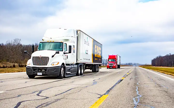 transportation-mobility-82750 Two people wearing eye protection look at a laptop propped on the hood of an electric vehicle as it charges inside a laboratory.